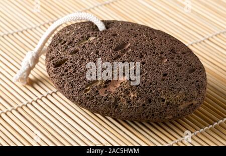 Black lava pumice stone spa or bath utensil used for peeling or callused skin removal on bamboo mat background Stock Photo