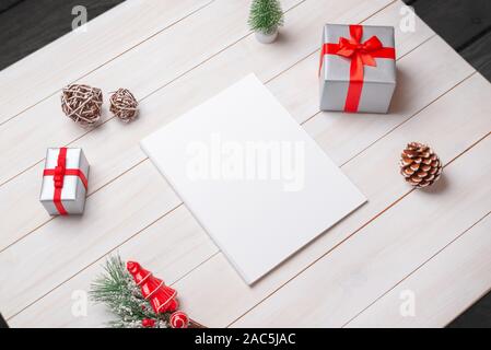 Blank magazine mockup on white wooden table surrounded by Christmas decorations. Stock Photo