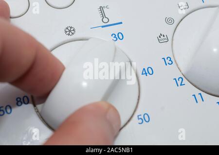 Man select a cold wash program on a washing machine Stock Photo