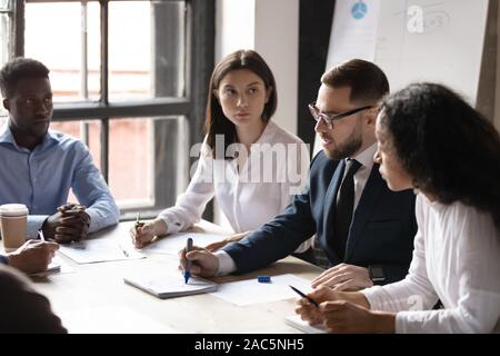 Concentrated mixed race young employees listening to confident male ceo. Stock Photo
