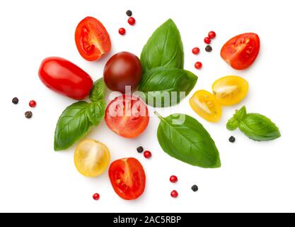 Composition with fresh cherry tomatoes isolated on white background. Red, yellow and brown tomatoes, basil leaves and peppercorns. Top view, flat lay Stock Photo