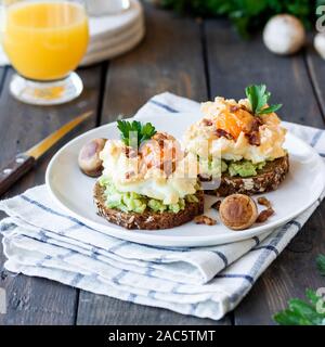 Sandwich with avocado and Orsini egg on cereal bread with toasted bacon for breakfast. Light and healthy breakfast made from simple products. Comforta Stock Photo