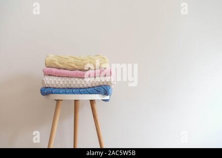 Pile of various woolen knitted blankets (sweaters) in pastel colors Stock Photo