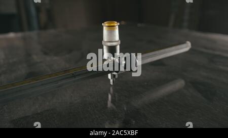 Forge. Smithy. Glass cutting and processing for fireplace doors. Circular glass cutter. Worker cut glass with glass cutting diamond. Polish an angle g Stock Photo