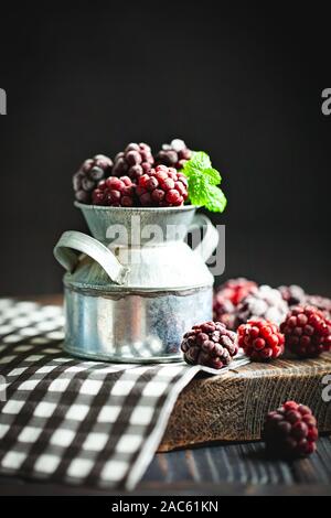 Frozen blackberries on a wooden table. Vertical. Stock Photo
