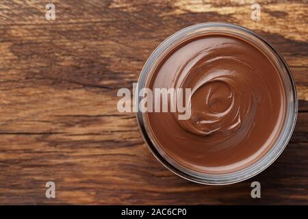 Chocolate spread or nougat cream in glass jar on wooden background, copy space Stock Photo