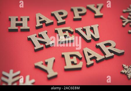 Red Happy New Year background with flat lay wooden letters on paper backdrop.Winter holiday wallpaper with hand made rustic elements Stock Photo