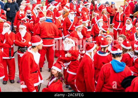 The yearly December Pilgrims Hospices 'Santas on the Run!' on the seafront at Herne Bay in Kent, England. View from above of lots of people dressed as Father Christmas standing around chatting to others. Stock Photo