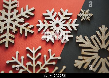 Wooden rustic snowflakes in flat lay on red & black Christmas background.Handmade snow flake figures for New Year home decor.Eco friendly natural wood Stock Photo