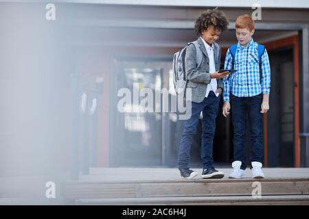 Two friends playing game on mobile phone together after school Stock Photo