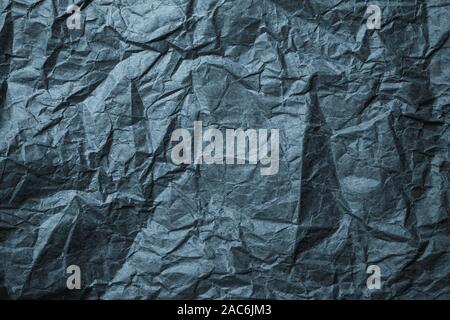Crumpled black paper background. Messy wrinkled parchment. Wrapping paper texture, craft sheet, old card. Stock Photo