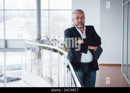 Arm crossed and standing in big white building with good daylight Stock Photo
