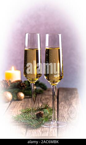 Two glasses of champagne with burning candle in background on rustic wooden table Stock Photo