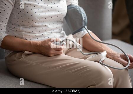 Closeup elderly woman manually takes blood pressure using medical device Stock Photo