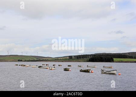 Rowing boats moored on Llyn Brenig Reservoir, with Wind Farm in distance Stock Photo