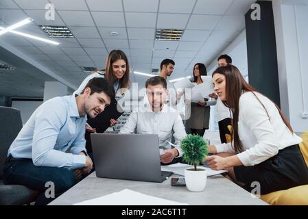 Working with laptop. Group of young freelancers in the office have conversation and smiling Stock Photo