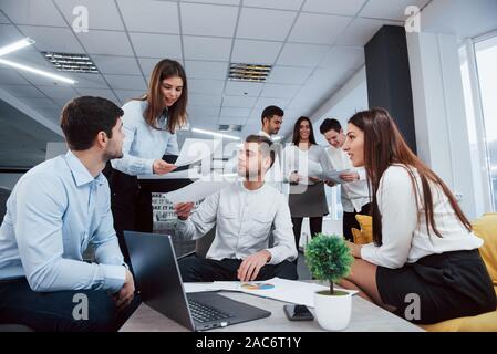 Working but fun atmosphere. Group of young freelancers in the office have conversation and smiling Stock Photo