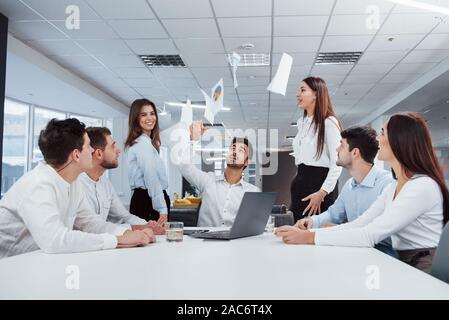Celebrating by throwing papers up. Job is done. Group of office workers happy to hit their own records and being successful Stock Photo