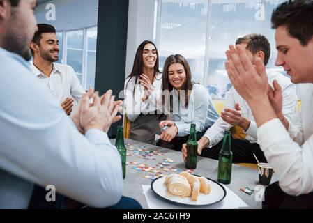 Everyone is smiling. Celebrating successful deal. Young office workers sitting near the table with alcohol Stock Photo