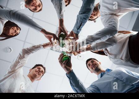 Photo from below. Knocking glasses in the office. Celebrating success Stock Photo