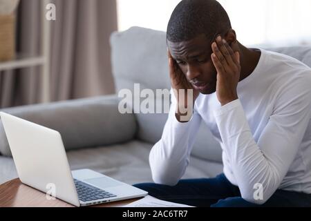Tired stressed young african american guy massaging temples. Stock Photo