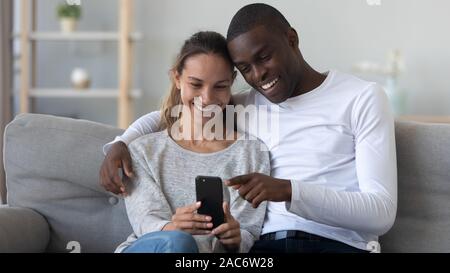 Happy young mixed race family couple using mobile phone. Stock Photo