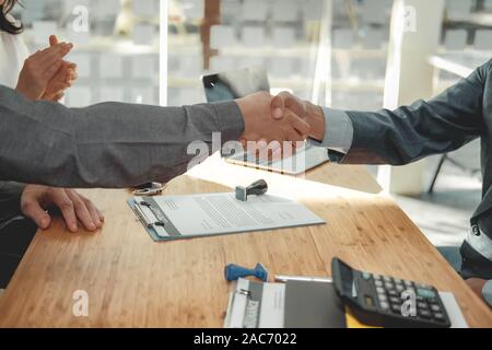 couple customer shaking hands with insurance mortgage broker lawyer realtor. client handshaking financial advisor bank worker making sale purchase dea Stock Photo