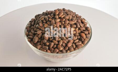 Pine nut rotate are on a table in a plate. Snack in transparent dish on an isolated white background are spinning moving. Delicious and healthy protei Stock Photo