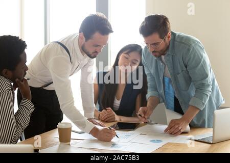 Multiracial employees do statistical analysis of data reviewing financial charts Stock Photo