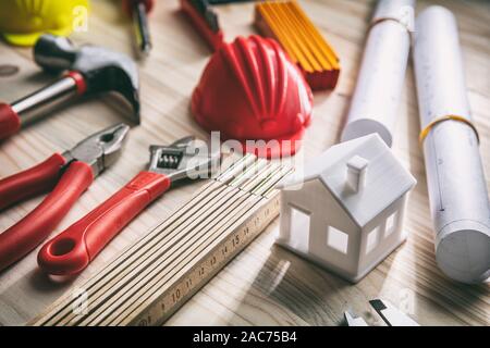 Construction, house renovation concept. Hand tools, hard hats and project blueprints on wood, close up view Stock Photo