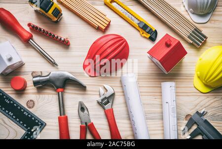Construction, house renovation concept. Hand tools, hard hats and project blueprints on wood, top view. Stock Photo