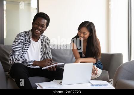 Cheerful multiracial colleagues preparing common task using pc Stock Photo