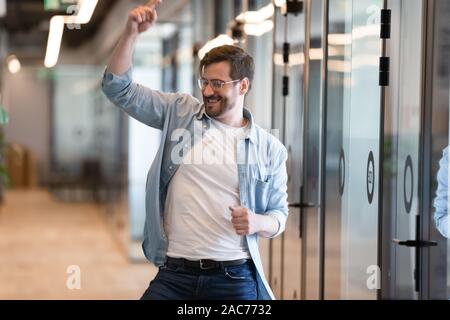 Funny male worker dancing in modern office hallway feels overjoyed Stock Photo