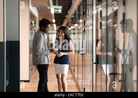 In office hallway diverse colleagues having friendly conversation Stock Photo