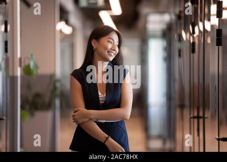 Attractive asian businesswoman standing in modern office hallway Stock Photo