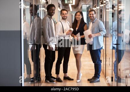 Multiethnic business people stands in office hallway pose for camera