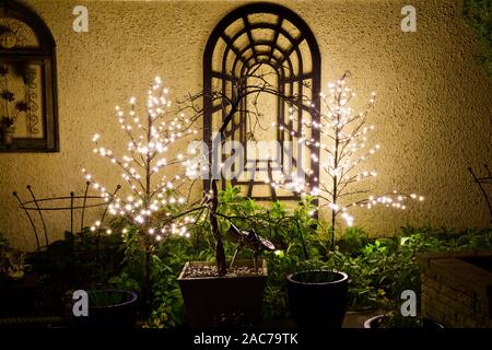 2 LED Christmas trees illuminating a garden border Stock Photo