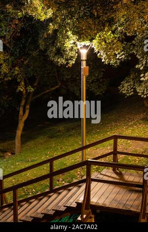 Wooden stairs illuminated by lamp in a park at night, city of Warsaw, Poland. Stock Photo