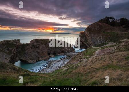 Lulworth, Dorset, UK. 1st Dec, 2019. UK Weather. Clouds building in the sky at sunset at Stair Hole at Lulworth in Dorset at the end of a cold sunny day on the first day of winter. Picture Credit: Graham Hunt/Alamy Live News Stock Photo