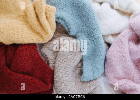Unfolded multi-colored knitted sweaters lie on the floor. Top view. Stock Photo