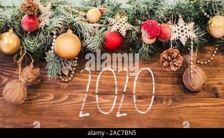 Chalk Inscription 2020 on a wooden background with decor of Christmas balls.New Year's photo - greeting card, banner, flyer. Stock Photo
