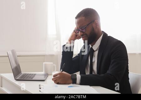 Exhausted entrepreneur working with documents in office Stock Photo