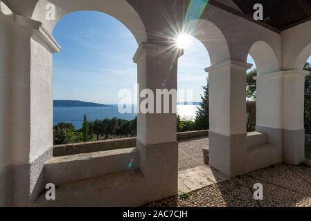 View through the arches of the porch of the chapel Sv. Salvadur on the island of Cres and Adriatic Sea and the afternoon sun, Kvarner Bay, Croatia Stock Photo