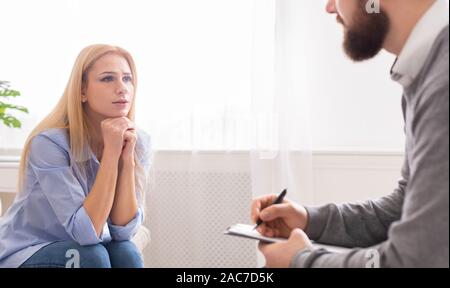 Sad woman talking with male therapist during personal session Stock Photo