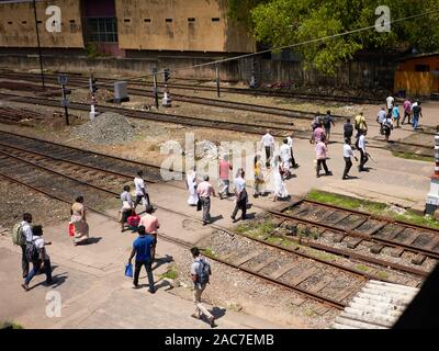 Local people cross the tracks at Fort Station in Colomobo, Sri Lanka Stock Photo