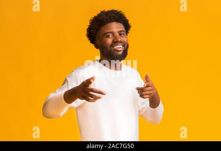 Cheerful black man greeting happily, indicating to camera Stock Photo