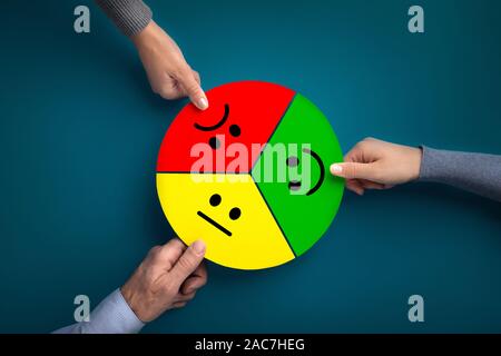 Customer hands giving feedback with smiley faces cards on blue Stock Photo