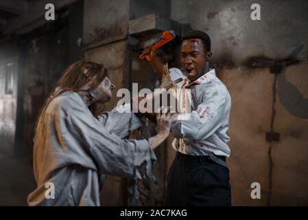 Man with pipe wrench kills female zombie, horror Stock Photo