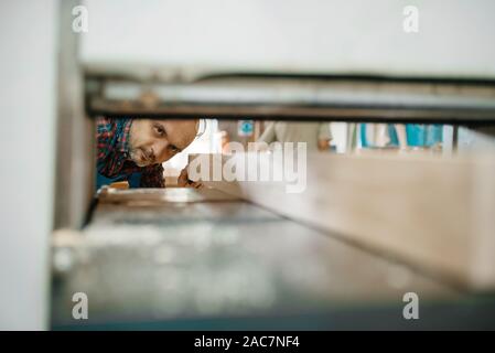 Carpenter works on plane machine, woodworking Stock Photo