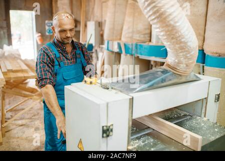Carpenter works on plane machine, woodworking Stock Photo